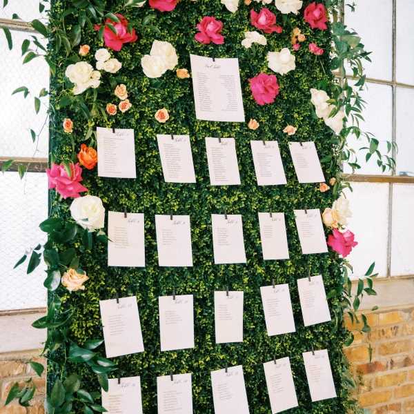 Vine wall with flowers and table seating arrangement cards.