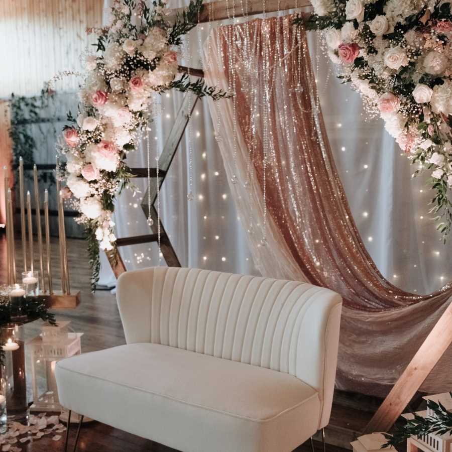 Wedding photobooth with pink and white flowers and white love seat.