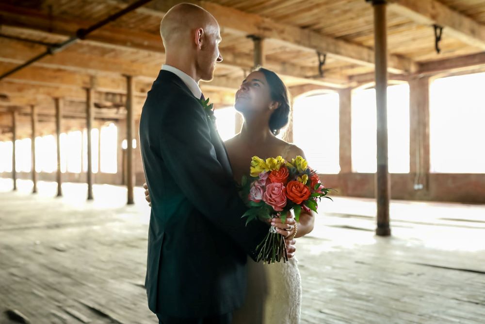 Bride and groom pose for portrait in the original weaving room.