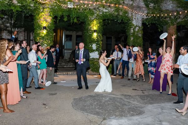 Couple dances in outdoor reception area surrounded by guests.