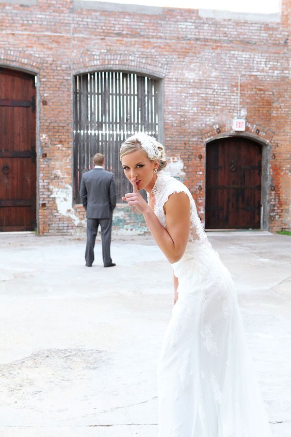 Bride getting ready to surprise groom. She is doing the "shoosh" motion toward the camera.