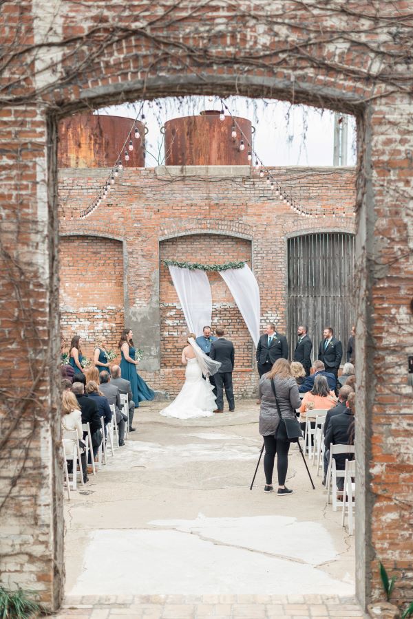 Couple facing pastor during outdoor wedding ceremony.