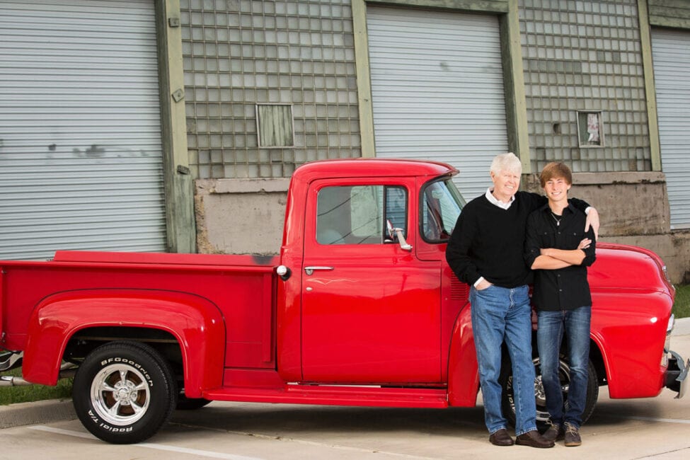 Grandfather and grandson in front of vintage red truck.