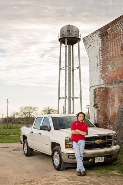 Guy standing in front of truck with The McKinney Cotton Mill water tower in the background.