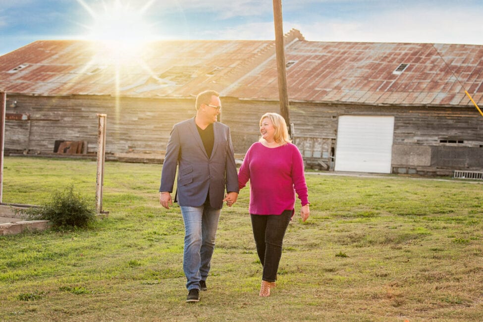 Local couple walking on lawn in front of The Cotton Mill's warehouse barn as the sun sets.